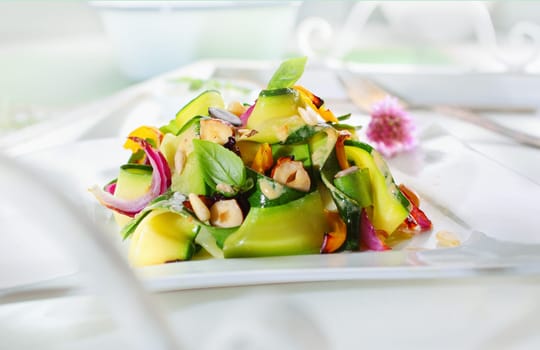 Gourmet Appetizing Fresh Green Salad with Plenty Elements, on White Table