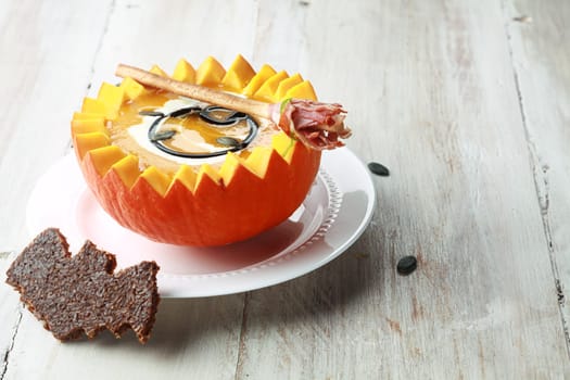 Pumpkin Soup with Bat Toast Crouton and Broomstick Bread Stick Served in Half a Pumpkin with Copyspace