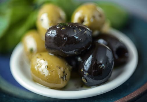 Small bowl of cured fresh black and green olives served as snacks and appetizers with shallow dof