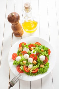 Italian salad with mozzarella cheese pearls, tomato, lettuce, herbs and croutons served with virgin olive oil and pepper