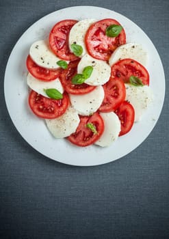 Italian Caprese salad viewed from above showing the colorful red and white pattern of alternating tomato and mozzarella cheese with fresh basil, with copyspace