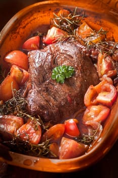 German braised meat with vegetables cooked in an earthenware casserole dish with fresh tomatoes in a rich gravy or sauce