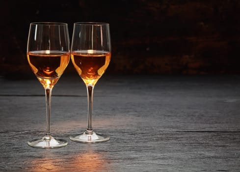 Pair of half-full half-empty wine glasses on stone surface