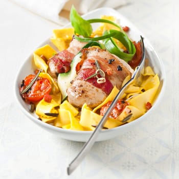 Traditional wide Italian pappardelle egg noodles with bacon, tomato, fresh herbs and spicy seasoning served in a bowl high angle view