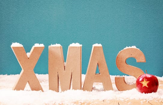 Xmas snow background with alphabet letters covered in a dusting of snow against a cool blue winter background with a colorful red bauble decorated with a star, copyspace for your Christmas message