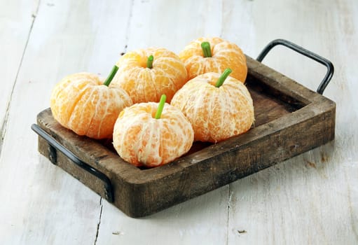 Clementine Oranges Decorated Like Pumpkins on Rustic Wooden Tray