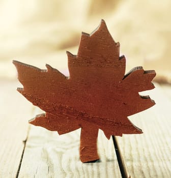 Rustic wooden Xmas maple leaf handicraft cut out decoration on an old weathered wooden table with textured background, square format