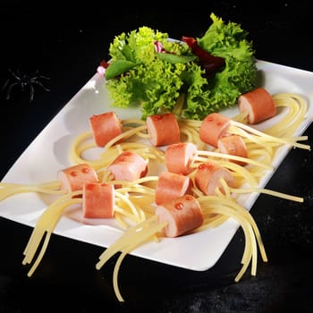 Hot Dog Wiener and Noodle Halloween Spider Snacks with Lettuce Garnish on White Plate on Black Background