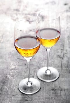Romantic lunch for two in the garden with a pair of wineglasses with white wine standing with their bowls touching on a rustic wooden outdoor table in sunlight