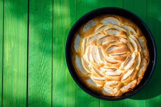 Appetizing freshly baked golden apple tart standing ready to serve on a green garden table in dappled sunlight for a tasty summer picnic