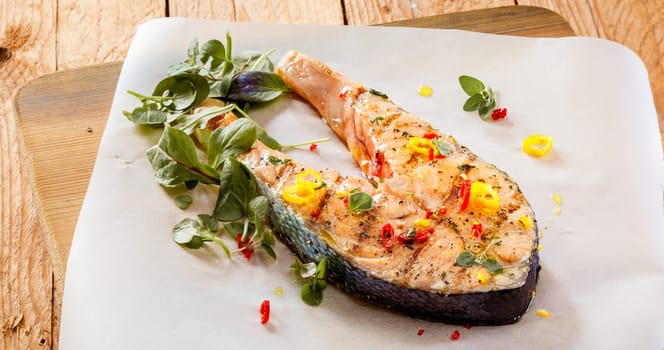 Grilled salmon fillet seasoned with spices, onion and herbs served on a wooden board in a seafood restaurant for a gourmet meal