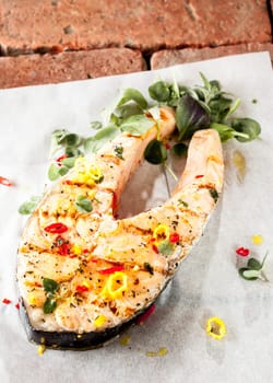 Gourmet grilled salmon cutlet steak seasoned with spices and fresh herbs served on a cloth on bricks for a delicious seafood dinner