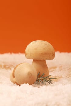 Rustic country Christmas background with two hand carved wooden mushrooms in a bed pf snow against an orange background for your seasonal greeting