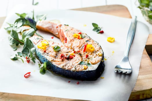 Cutlet of grilled gourmet salmon seasoned with fresh herbs and spices served on a wooden board in a seafood restaurant , low angle view