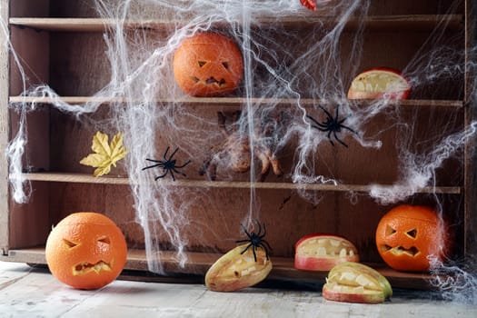 Halloween pantry with spider web covered shelves crawling with large black spiders and orange jack-o-lanterns with scary faces and a bat flying overhead