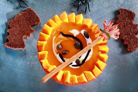Halloween Pumpkin Soup Served in Half a Pumpkin with Bat Shaped Crouton Toasts and Broomstick Bread Stick from Above