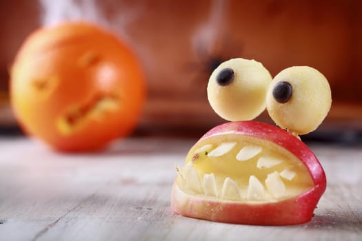 Fun scary homemade Halloween table decoration of fresh apple slices in the form of an open mouth with teeth topped by a pair of round googly dough eyes