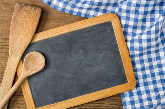 Slate table with cooking spoons on a blue checkered tablecloth