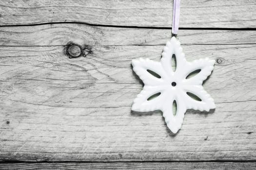 Christmas snowflake background with a white snowflake decoration hanging against old cracked wooden boards with copyspace for your Xmas message