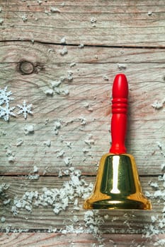 Colorful red hand bell with snowflakes on old wooden boards for a rustic country style Christmas background with copyspace