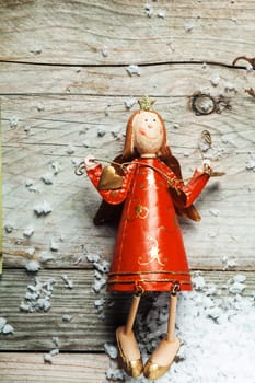 Vintage wooden Christmas angel in a colorful red dress in country crafts style on an old wooden background with copyspace