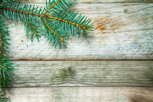 Seasonal background with a pine branch arranged as a corner border on old rustic textured wooden boards with copyspace for your Christmas message