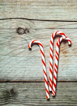 Colorful red and white striped Xmas candy canes on a rustic wooden background with copyspace for your seasonal Christmas greeting or invitation