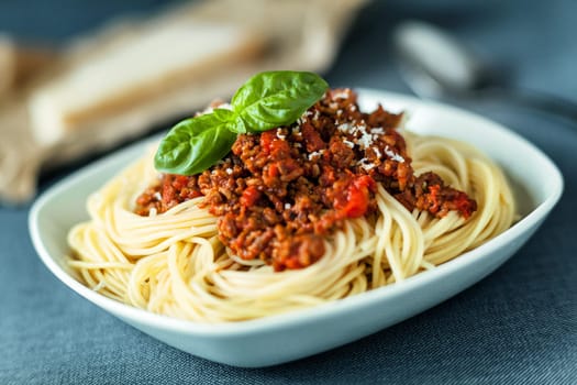 Traditional Italian spahgetti Bolognaise or Bolognese with cooked pasta noodles topped with a spicy tomato based meat sauce garnished with fresh basil