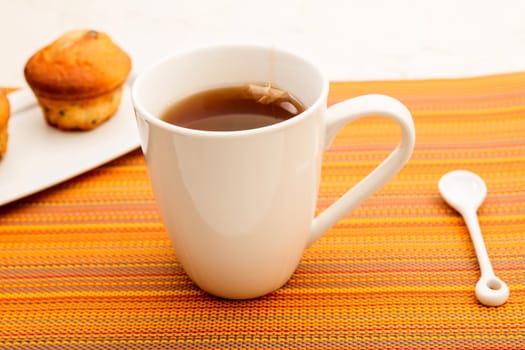 Vanilla with chocolate chips Muffins on a white plate with  a cup of tea.