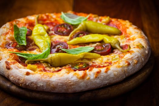 Homemade pizza with dried tomatoes, hot peppers and basil