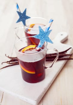 Two festive glasses of Christmas mulled wine or punch seasoned with spices and orange slices served with a straw decorated with a star