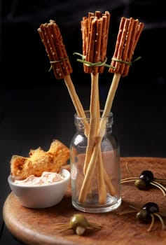 Creative Halloween snacks and appetizers with witches broomsticks made from bread sticks and pretzels with creepy spiders of olives and spaghetti on a table at a Halloween celebration