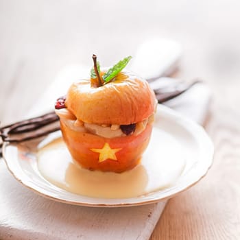 Scary Halloween dessert, a baked stuffed apple decorated with a star and cut out gaping mouth showing teeth garnished with fresh mint