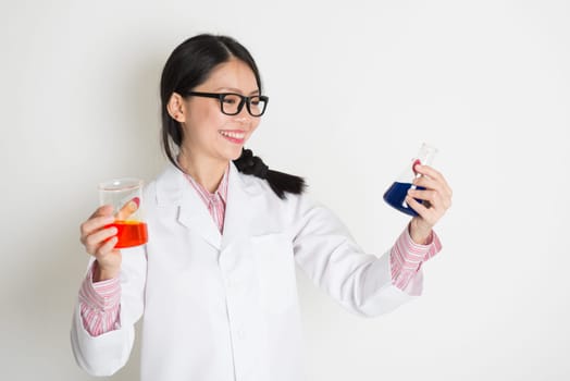Asian girl microbiology student doing liquid sample test analysis, on plain background.
