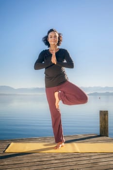 An image of a pretty woman doing yoga at the lake