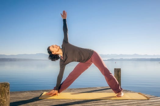 An image of a pretty woman doing yoga at the lake