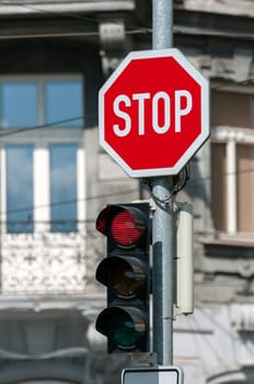 Red traffic light on and stop sign.