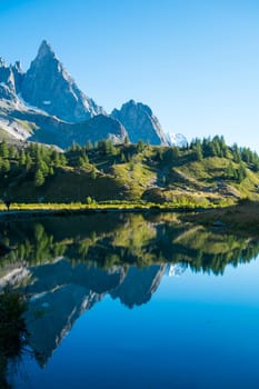 Combal Needles reflected on Combal Lake water on a sunny day in Val Veny, in Italy.