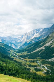 Early morning in Val Ferret valley in Italy, with overcast sky and rocky mountain range