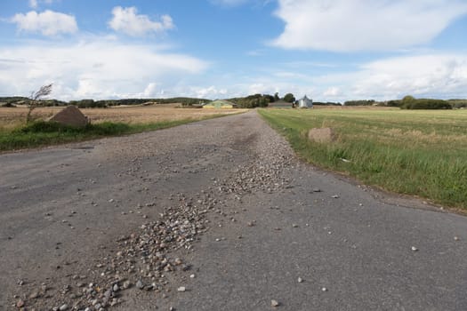 Long rocky dirt road leading to a farm in the field