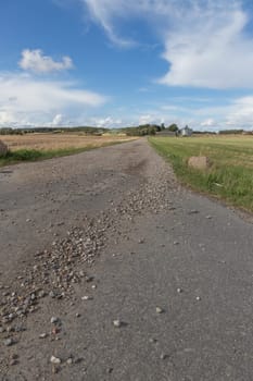 Long rocky dirt road leading to a farm in the field