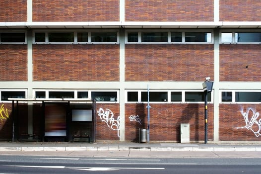 The photograph of a bus stop on a strikingly brick house wall.