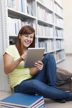 Happy student using digital tablet in library