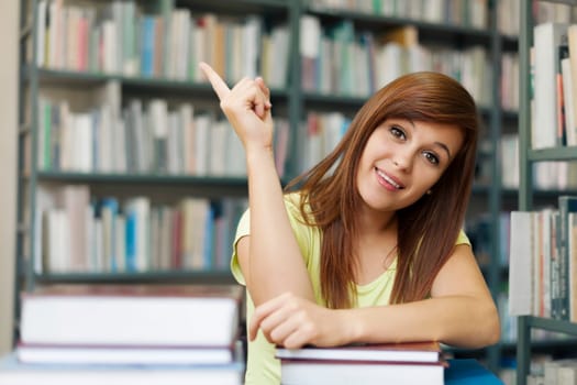 Beautiful student pointing at copyspace