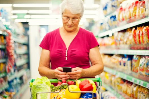 Senior woman texting on mobile phone at supermarket