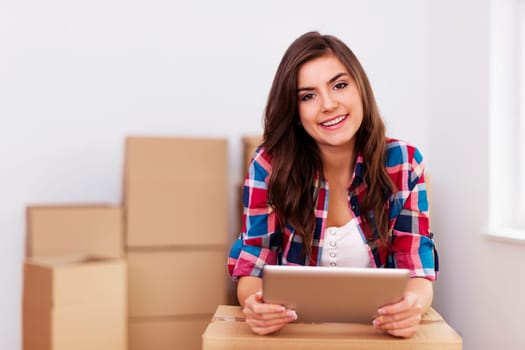 Young woman using digital tablet during moving in new apartment