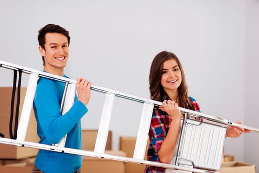Young happy couple with a ladder during moving in new home