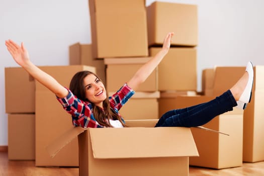 Cheerful woman sitting in a cardboard box