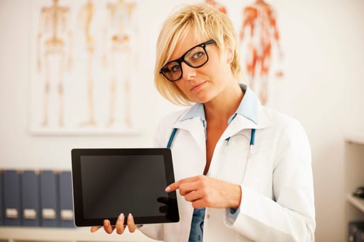 Serious female doctor pointing at digital tablet
