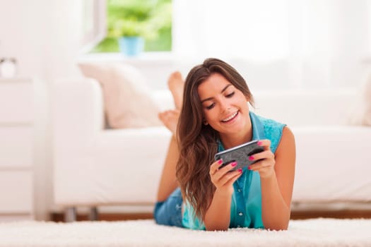 Happy young woman text messaging at home
